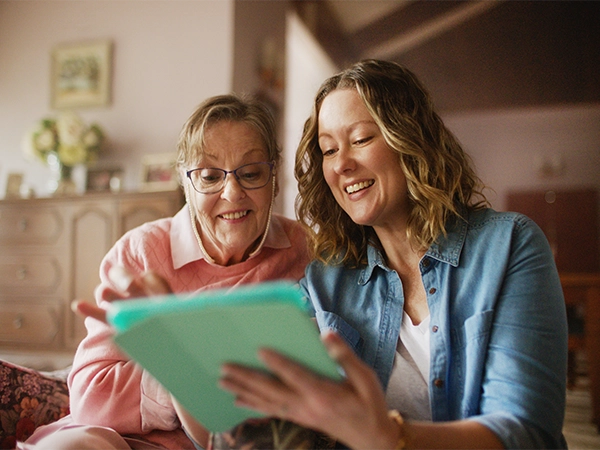 Two women reading their ipad in a cozy home setting.