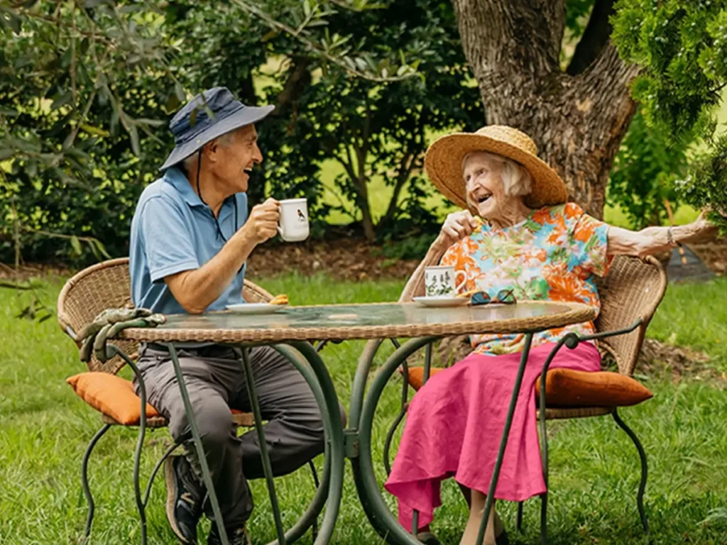 Client and support worker having tea and chatting in a garden.