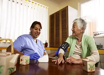 Elderly asian woman with clinical nurse, taking her blood pressure within her own home