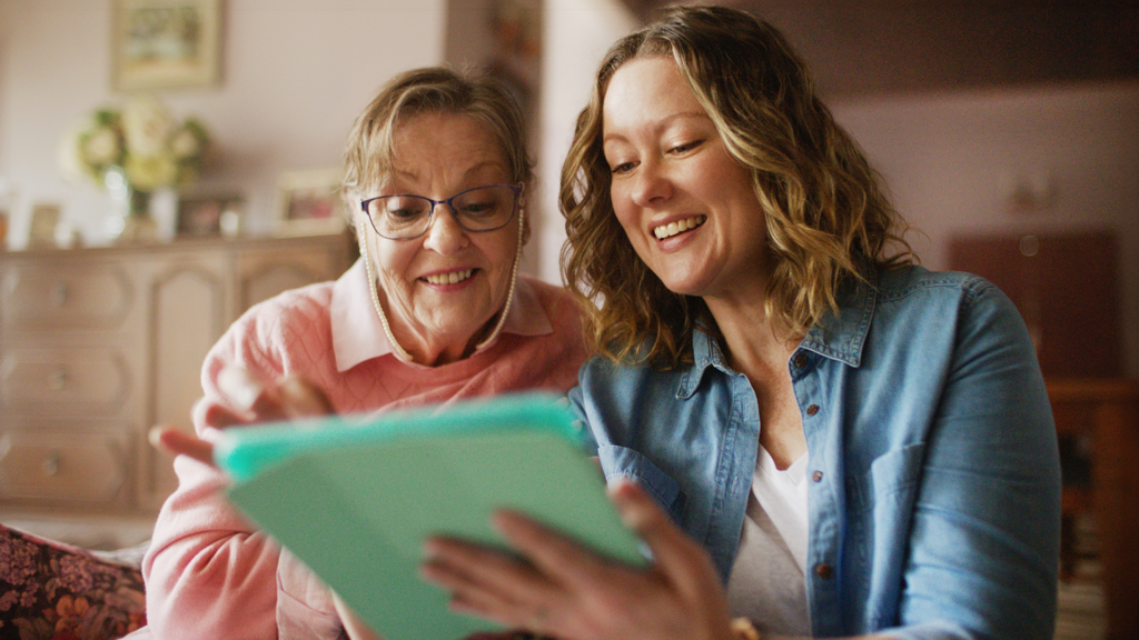 Two women use a tablet together.