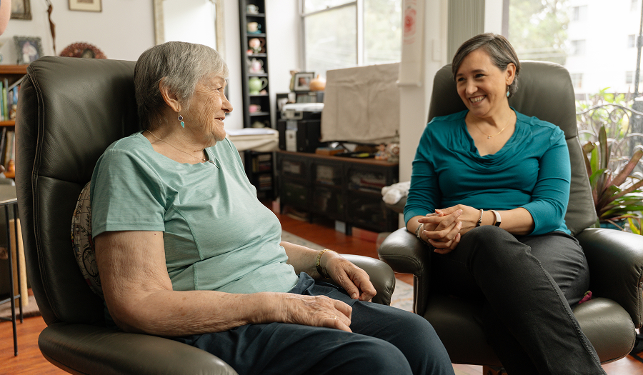 Older woman chatting with a support worker during a home visit.