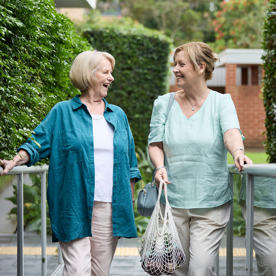 Two women walking outdoors together and smiling.