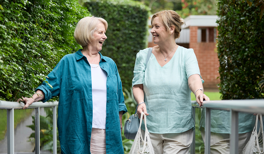 Two women walking outdoors together and smiling.